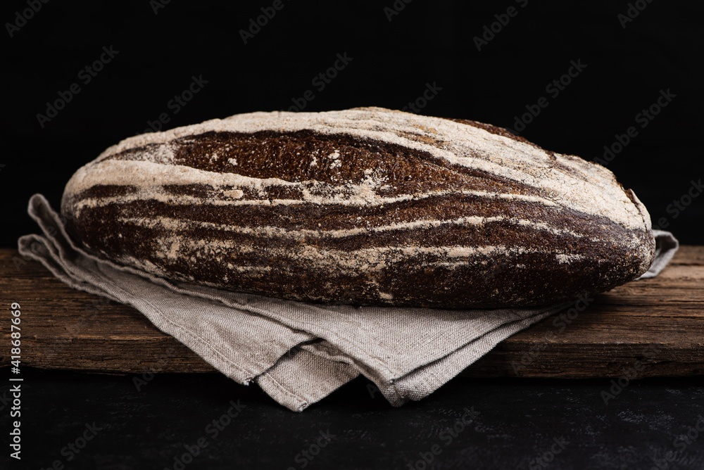 Freshly baked homemade artisan sourdough rye bread on wooden board. Closeup of farmhouse bread at leaven. Low key.
