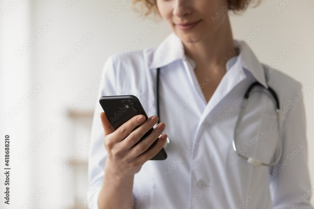 Crop close up of female doctor in white medical uniform hold modern smartphone browse wireless internet. Woman GP use cellphone consult hospital patient online on gadget. Technology concept. Crop close up of female doctor in white medical uniform hold modern smartphone browse wireless internet. Woman GP use cellphone consult hospital patient online on gadget. Technology concept.