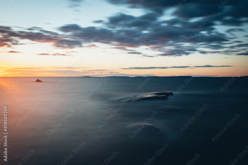 Scenic long exposure sunset over rocks the sea in Faboda, Finland