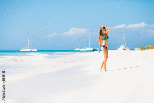 Young attractive blonde girl with perfect sport body in bikini on the tropical summer beach
