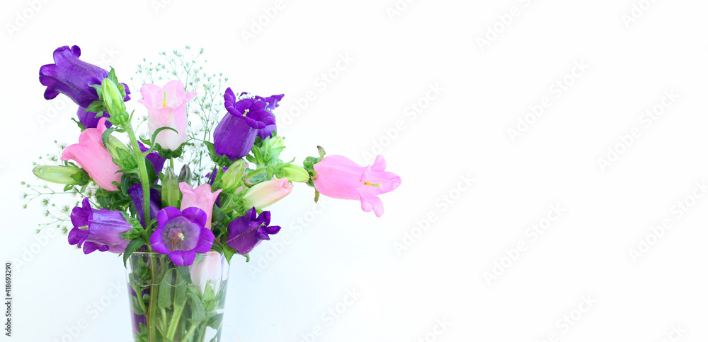 Obraz premium spring bouquet of purple, white and pink bell flowers over white wooden background