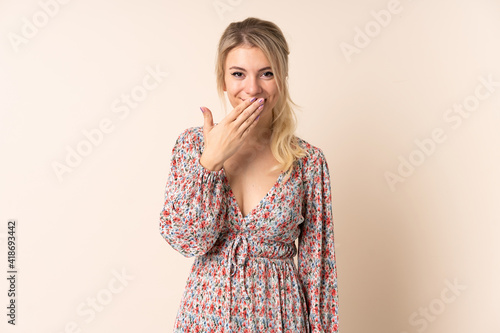 Blonde woman over isolated background happy and smiling covering mouth with hand