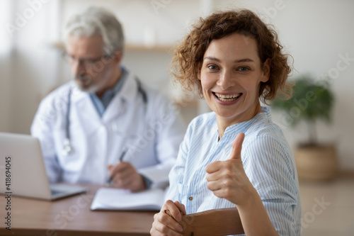 Tableau sur toile Overjoyed young Caucasian female patient show thumb up satisfied with consultation with doctor