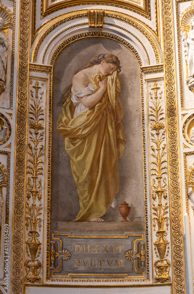 Close-up on fresco decorating niche inside catholic church in Rome, showing a beautiful young woman crying