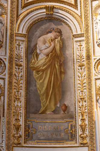 Close-up on fresco decorating niche inside catholic church in Rome, showing a beautiful young woman crying