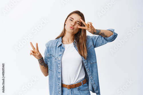 Canvas Print Portrait of happy beautiful woman in casual clothes, showing v-signs and pucker