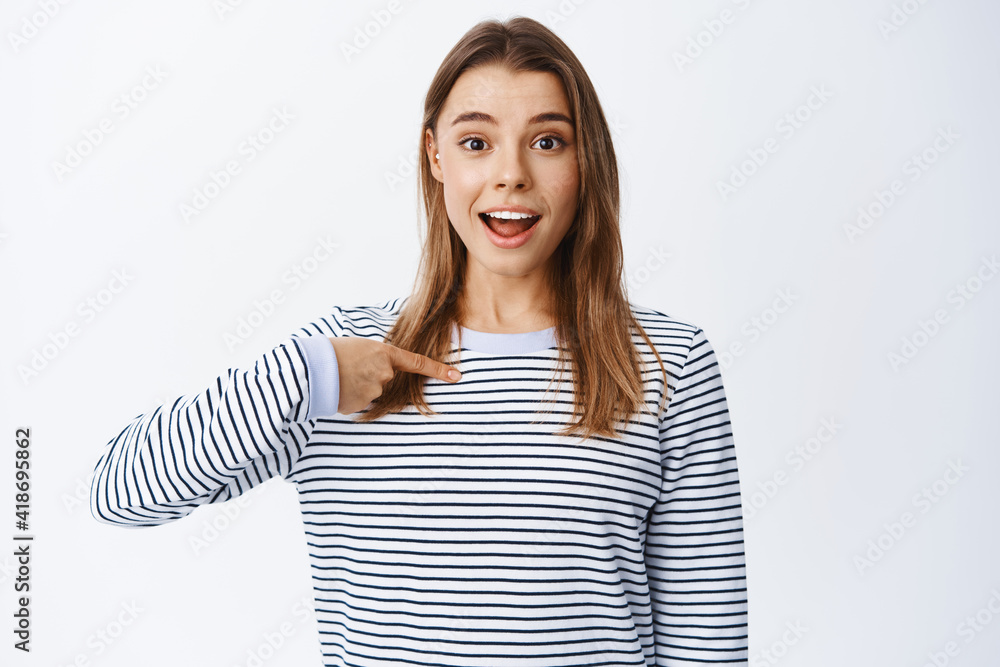 Cheerful blond girl pointing at herself and looking hopeful, volunteering, wanting to be picked or chosen, asking for job, standing over white background Cheerful blond girl pointing at herself and looking hopeful, volunteering, wanting to be picked or chosen, asking for job, standing over white background