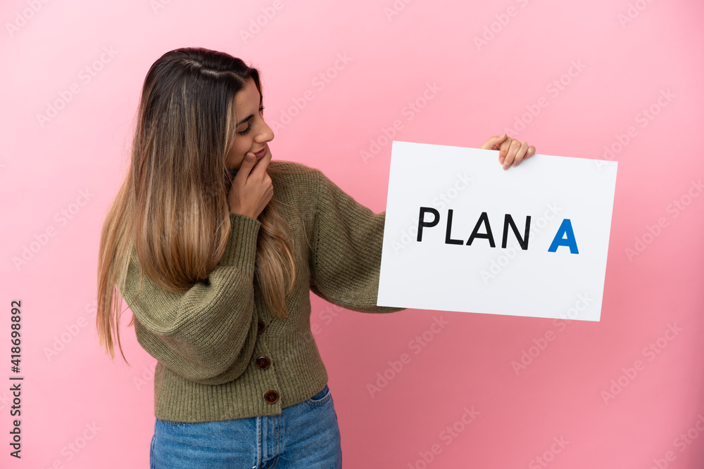 Young caucasian woman isolated on pink background holding a placard with the message PLAN A and thinking Young caucasian woman isolated on pink background holding a placard with the message PLAN A and thinking