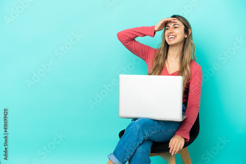 Young caucasian woman sitting on a chair with her pc isolated on blue background has realized something and intending the solution © luismolinero