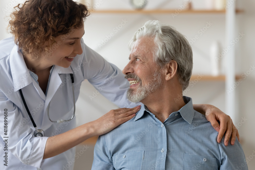 Obraz premium Caring Caucasian female nurse support caress optimistic overjoyed senior Caucasian man patient. Smiling woman doctor comfort mature male during home visit. Elderly healthcare, geriatrics concept.