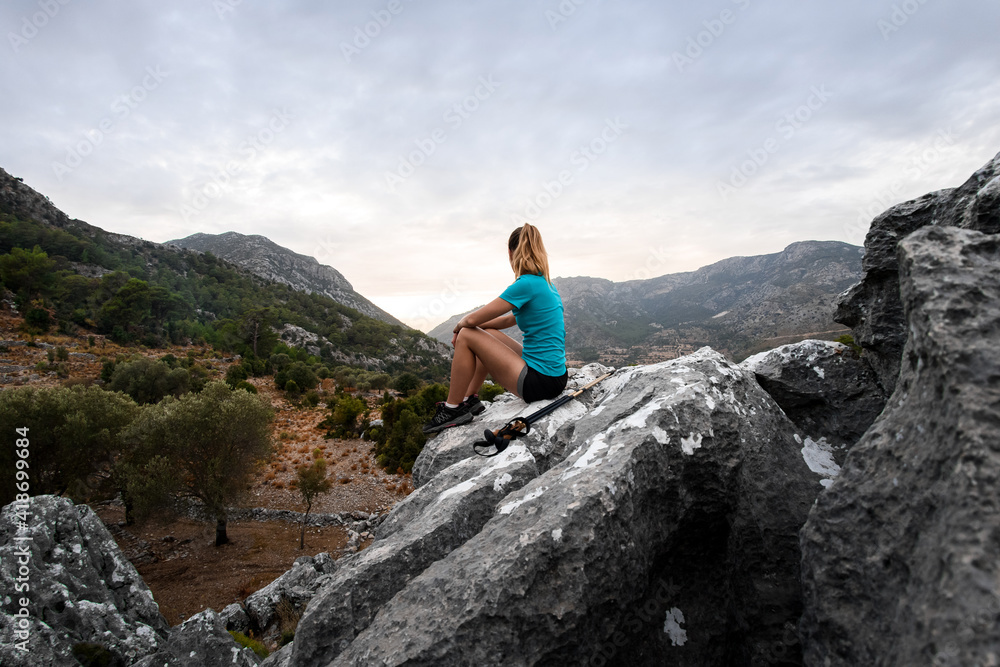 great view on woman resting on stone and enjoying beautiful mountains landscape.