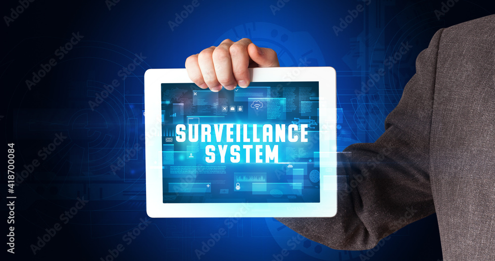 Young business person working on tablet and shows the digital sign: SURVEILLANCE SYSTEM Young business person working on tablet and shows the digital sign: SURVEILLANCE SYSTEM