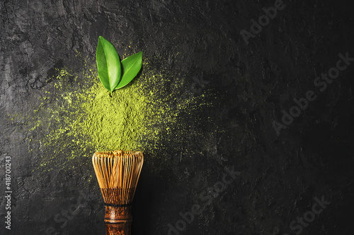 Fotografie Matcha tea powder on dark background with whisk and leaves with copy space