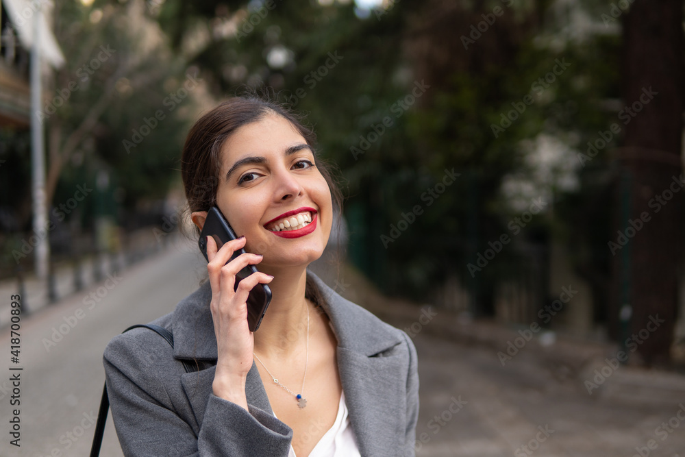 Happy businesswoman talking on the mobile phone with a beautiful smile and red lipstick Happy businesswoman talking on the mobile phone with a beautiful smile and red lipstick
