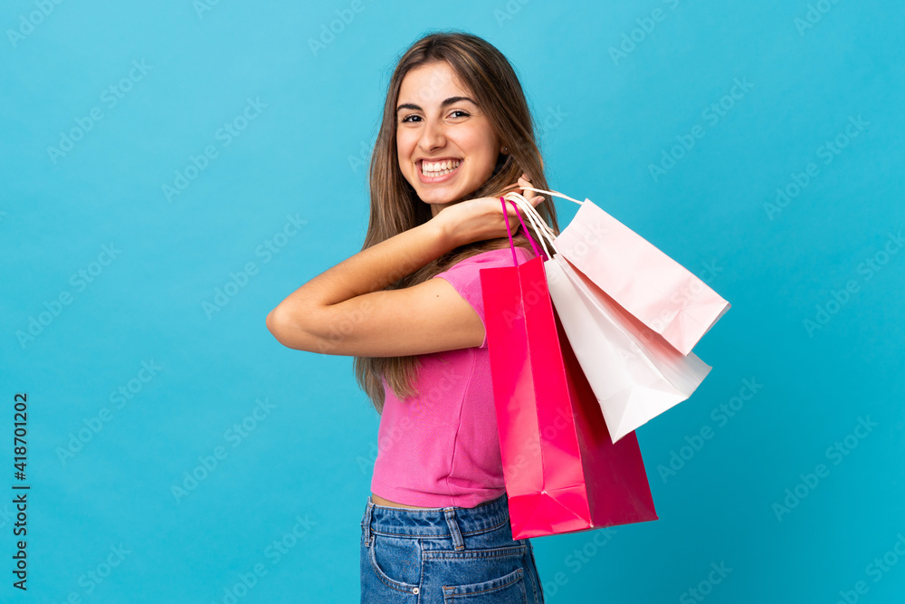 Young woman over isolated blue background holding shopping bags and smiling Young woman over isolated blue background holding shopping bags and smiling