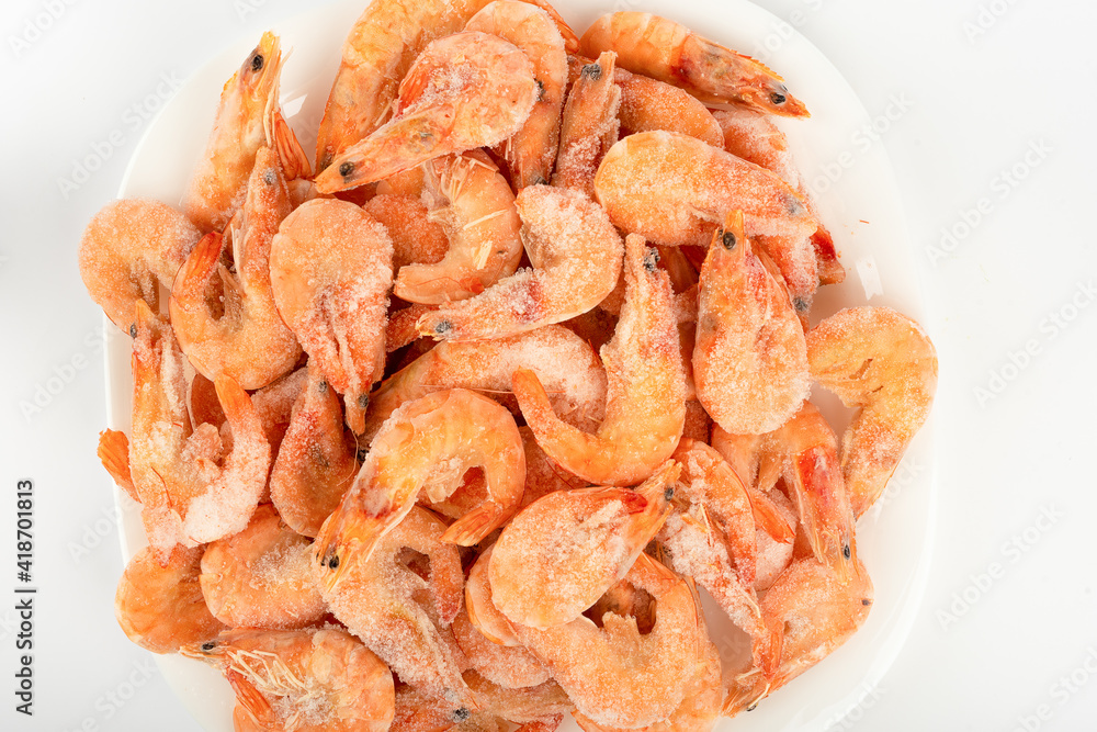 Top view of frozen shrimp on a white plate over a light background. Close up. Top view of frozen shrimp on a white plate over a light background. Close up.
