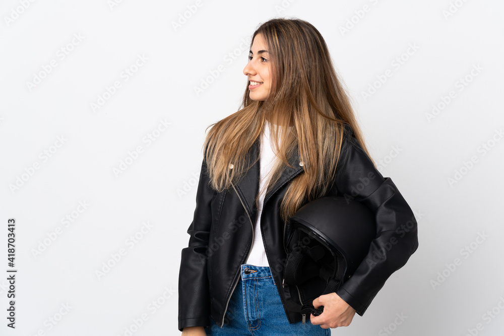 Young Woman holding a motorcycle helmet over isolated white background looking to the side Young Woman holding a motorcycle helmet over isolated white background looking to the side