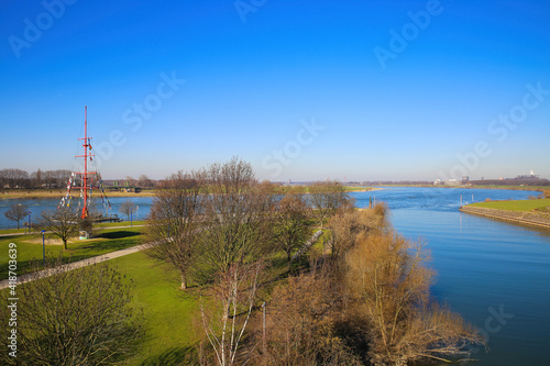 View over green pasture pensinsula (Mühlenweide) at river rhine against blue sky in winter - Duisburg, Germany photo