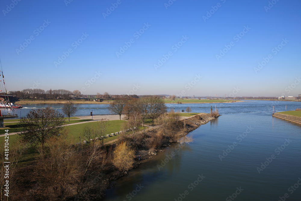 View over green pasture pensinsula (Mühlenweide) at river rhine against blue sky in winter - Duisburg, Germany