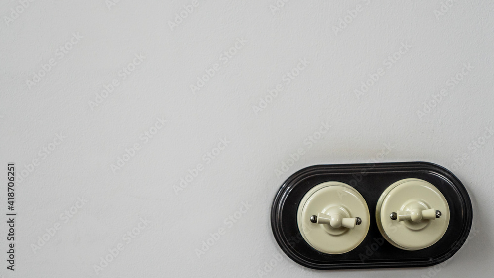 A old-fashioned switch wires is installed on a empty concrete wall. Electric switch with two vintage switches. The theme of energy and electrification with space to copy. Space for text. A old-fashioned switch wires is installed on a empty concrete wall. Electric switch with two vintage switches. The theme of energy and electrification with space to copy. Space for text.