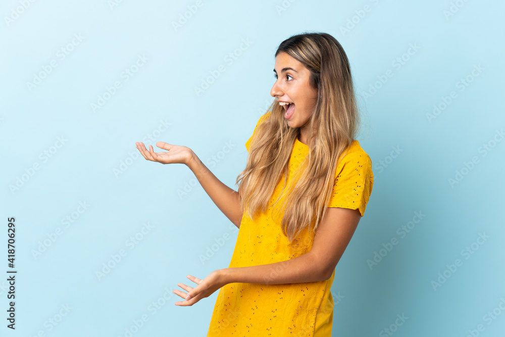 Young hispanic woman over isolated blue background with surprise expression while looking side Young hispanic woman over isolated blue background with surprise expression while looking side