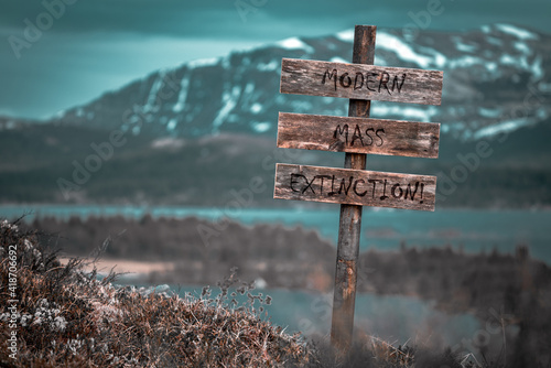 Foto modern mass extinction text quote engraved on wooden signpost outdoors in landscape looking polluted and apocalyptic
