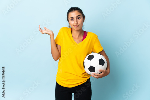 Young hispanic football player woman over isolated on blue background having doubts while raising hands © luismolinero