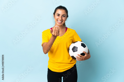 Young hispanic football player woman over isolated on blue background inviting to come with hand. Happy that you came © luismolinero