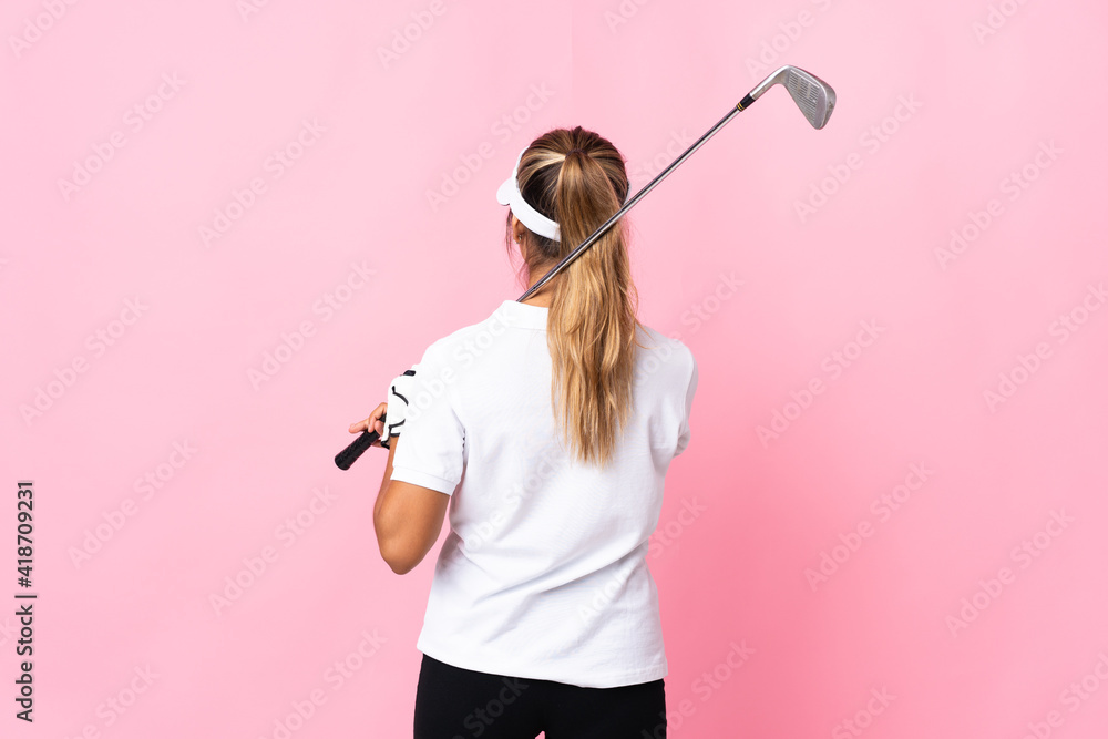 Young hispanic woman over isolated pink background playing golf and in back position Young hispanic woman over isolated pink background playing golf and in back position