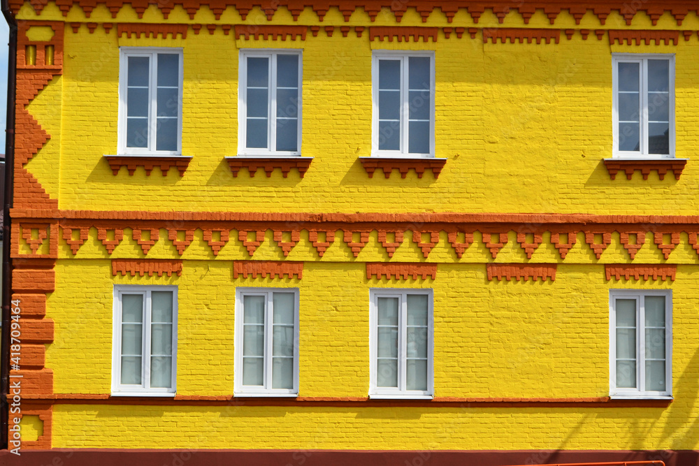 The facade of a old house made of brick painted in yellow and windows, beautiful bright background The facade of a old house made of brick painted in yellow and windows, beautiful bright background