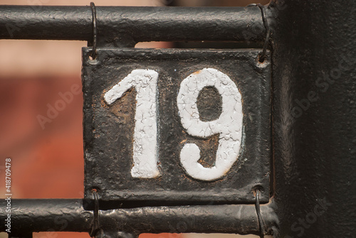 Old retro weathered cast iron plate with number 19 closeup photo