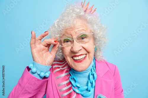 Obraz na plátne Portrait of beautiful elderly grey haired woman keeps hand on rim of spectacles