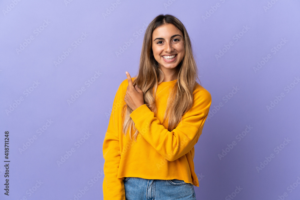 Young hispanic woman over isolated purple background pointing to the side to present a product Young hispanic woman over isolated purple background pointing to the side to present a product