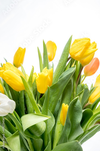 bouquet of yellow bright tulips in a glass transparent vase on a white background.