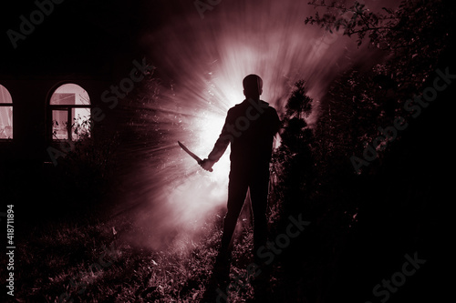 strange light in a dark forest at night. Silhouette of person standing in the dark forest with light. Horror halloween concept. strange silhouette in a dark spooky forest at night