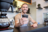 Glass of coffee in outstretched hand of smiling barista