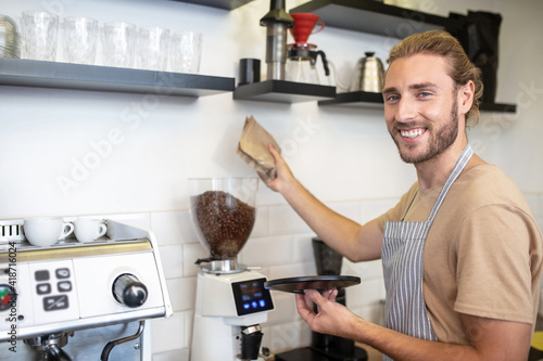 Smiling man near coffee grinder in his cafe
