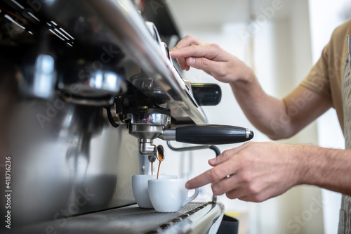 Male hands near coffee machine pressing start