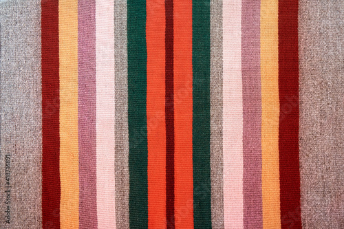 Stylish ethnic handmade carpet with bright stripes on floor