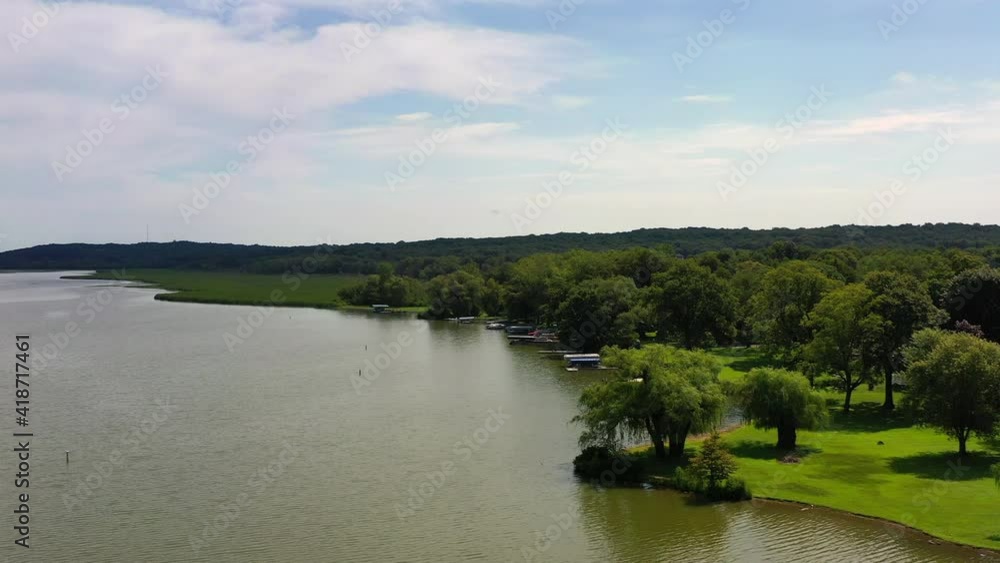 Aerial shot of boats and houses amidst green trees at lakeshore, drone flying forward over lake against sky on sunny day - Lake Como, Wisconsin Aerial shot of boats and houses amidst green trees at lakeshore, drone flying forward over lake against sky on sunny day - Lake Como, Wisconsin