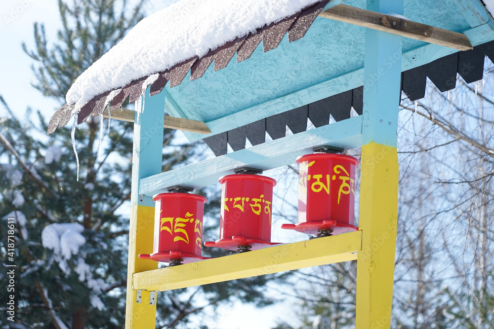 Buddhist prayer drums in winter under the snow. The drum has a mantra in Tibetan 