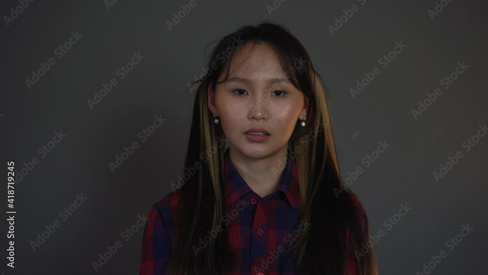 Asian Good-Looking Girl Grey Background. Emotions Of Thinking. A Woman is upset Asian Good-Looking Girl Grey Background. Emotions Of Thinking. A Woman is upset