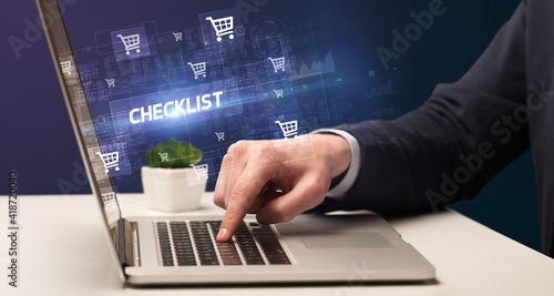 Businessman working on laptop with CHECKLIST inscription, online shopping concept