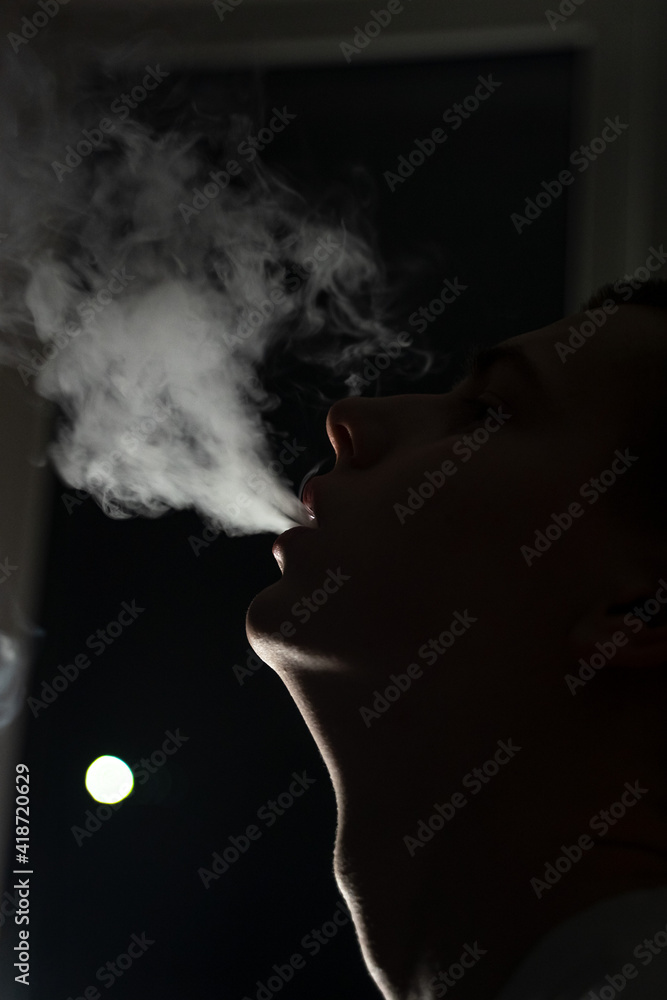 close-up of teenager smoking vape, blowing out big puffs of smoke