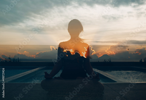 Multiple exposure image of Clouds and sunset. Pranayama in lotus asana woman