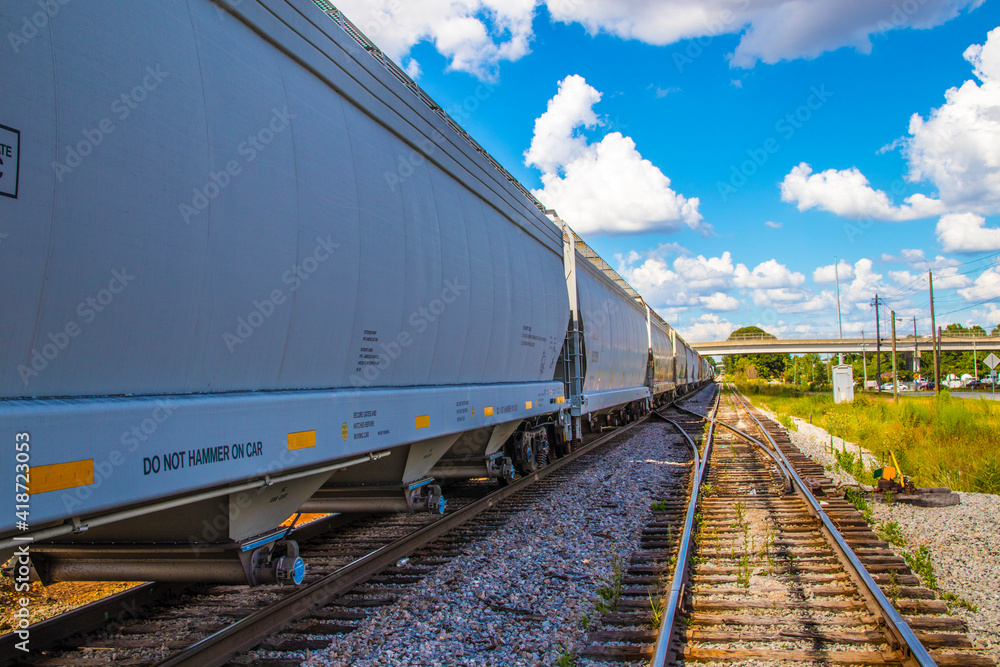 A long train and train track with blue sky and clouds background