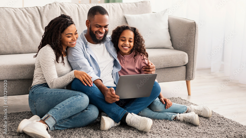 Happy black family using laptop in living room Happy black family using laptop in living room