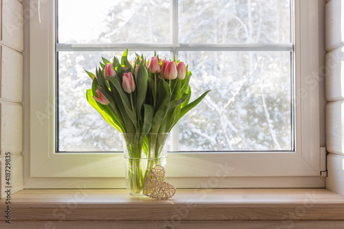 Bouquet of beautiful pink tulips on a wooden windowsill. White window in a Scandinavian style wooden house overlooking the garden, pine forest. Spring concept, Happy 8 March, Women's Day
