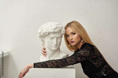girl hugs a bust of david on a white background