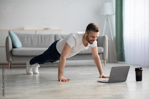 Happy middle-aged man in sportswear doing push-ups at home